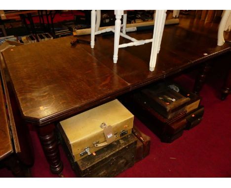 A late Victorian oak extending dining table, having wind-out action, two extra short drop-in leaves, and raised on ring turne