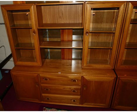 An Ercol elm Windsor range wall cabinet, the modular upper section having twin glazed doors, open compartment, and single she