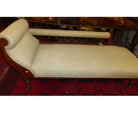A late Victorian walnut and green floral silk damask upholstered chaise longue, having spindle back columns, and raised on ri