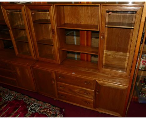 An Ercol elm Windsor range wall cabinet, the modular upper section having twin glazed doors, open compartment, and single she