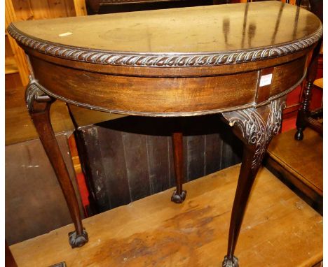 An early 20th century mahogany demi-lune baize lined fold-over card table, having rear pull-out leg, gadrooned edge raised on