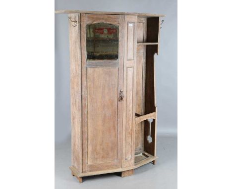 An Edwardian Arts and Crafts limed oak hall cupboard, the single panelled door flanking an open shelf above a stick stand, he