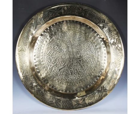 A large Arts and Crafts circular brass charger, chased with overall stylized foliage, diameter 90cm.
