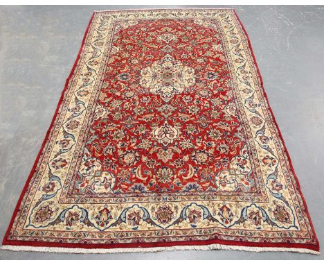 A Najafabad carpet, Central Persia, late 20th century, the red field with a lobed medallion, supported by leaves and palmette