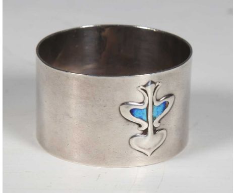 An Arts and Crafts silver napkin ring, the front enamelled and embossed with a stylized flower motif, Birmingham 1905 by Henr
