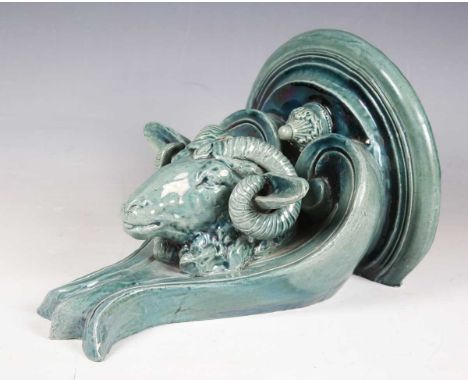 A late Victorian pottery wall bracket, the hemispherical top above a ram's head, flanked by a pair of scrolls, covered in a b