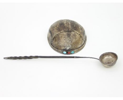 A human skull crown with silver coloured metal mounts and jewelled border and a toddy ladle with Georgian coin set to the bas