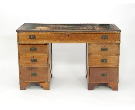 An oak kneehole desk fitted a surround of seven drawers on bracket feet, 127cm wide