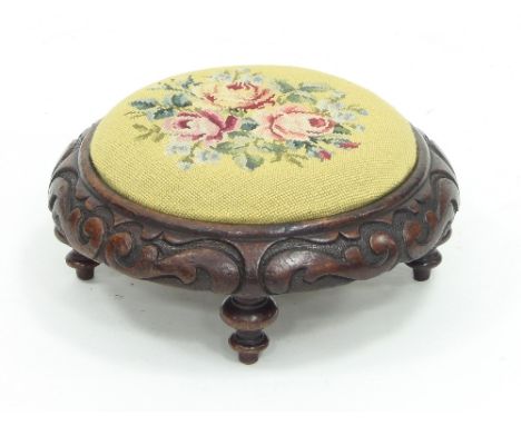 An oak circular foot stool with carved surround on four turned legs, gros point needlework, floral design to pad, 35.5cm diam