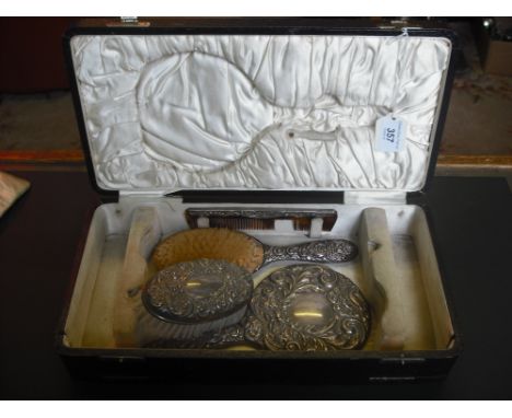 A four piece silver backed dressing table set, comprising: two brushes, hand mirror and comb in an associated leather case.