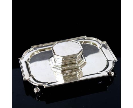 An Edwardian silver desk stand, rounded rectangular form with inkwell and pen tray surround with four hoof feet, by Thomas Br