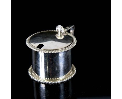 A late Victorian silver drum-shaped mustard pot, with cast gadrooned rims and blue glass liner with shell thumb-piece, by Gol