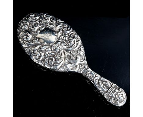 A heavy late Victorian silver dressing table hand mirror, allover relief embossed foliate decoration, with oval bevel-glass m