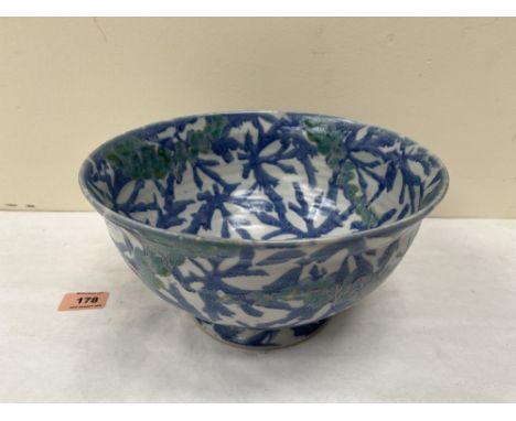 Attrib. to Janic Tshalenko (Dartington). A ceramic bowl painted in shades of blue and green with foliage and berries. 10' dia