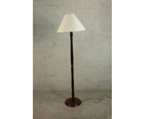 A 20th century mahogany standard lamp, with a turned stem and circular base and white shade. H.154 Dia.46cm. 