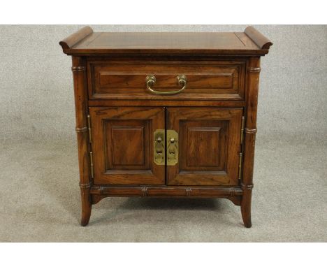 A late 20th century Chinese elm altar style cabinet, with a long drawer over two cupboard doors with brass swing handles, the