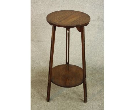 An Arts &amp; Crafts oak lamp table, with a circular top on three pierced legs joined by a circular undertier. H.80 W.40 D.40