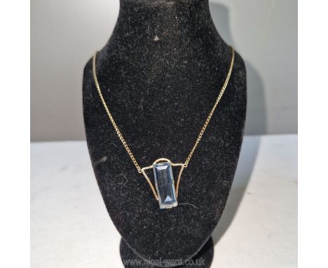 A art deco gold pendant on chain hallmarked 9 carat and set with a baguette cut transparent blue semi-precious stone- presume