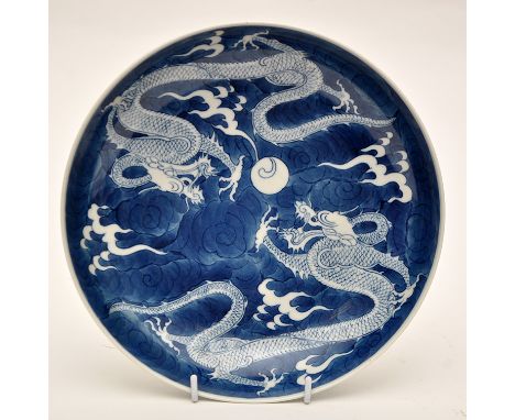 Chinese blue and white saucer dish, the interior with two dragons chasing a flaming pearl upon a blue cloud ground, the exter