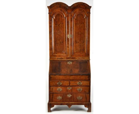 A George I and later walnut bureau bookcase, the double arched cornice above a pair of bevelled panel doors opening to reveal