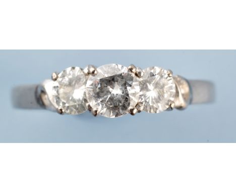 A three stone diamond ring, the brilliant cut diamonds in high pierced setting, on white metal shank stamped '18k', ring size