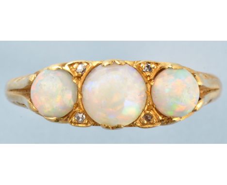 An opal and diamond ring, the three graduated circular cabouchon opals separated by diamonds, above scrollwork mount, on 18ct