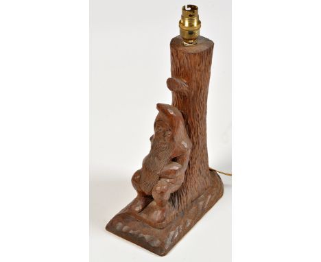 Thomas "Gnomeman" Whittaker: a carved oak table lamp decorated with a gnome leaning against a tree, 13in. high.See illustrati