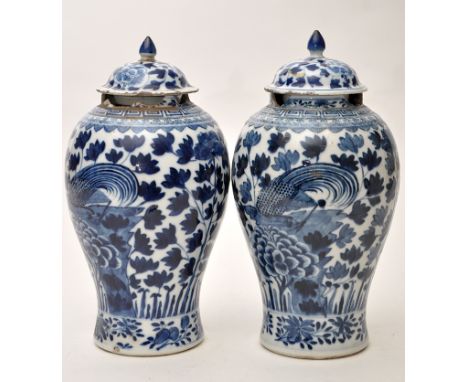 Pair of Chinese blue and white 'Phoenix' vases and covers, the birds perched amongst foliage and flower blooms between floral