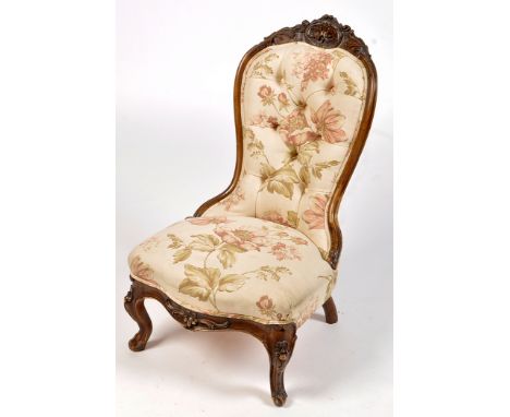A Victorian walnut carved nursing chair, with floral carved cresting rail above button back and seat upholstered in floral ma
