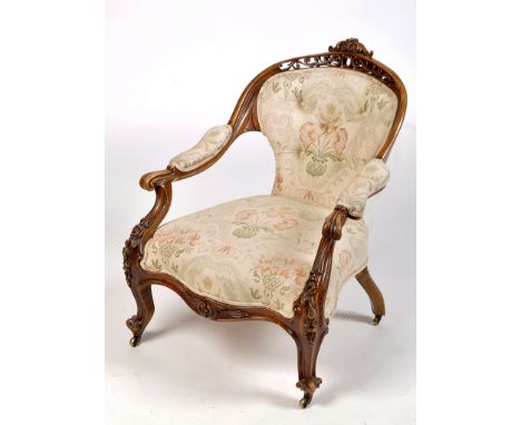 A Victorian carved walnut nursing chair, with pierced scrolling cresting rail above button back, arms and seat upholstered in