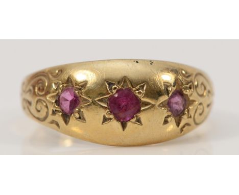 A 9ct gold ruby three stone dress ring with engraved shoulders, O 1/2, 3g