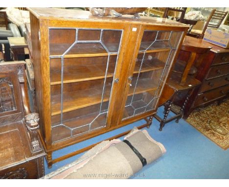 A 1940's oak glazed Display Cabinet/Bookcase; moulded edge top over pair of opposing leaded glazed doors on bobbin turned leg