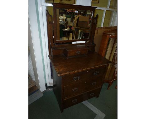 A 1920's Oak Dressing Chest having rectangular mirror in fretcut supports with shelf and jewellery drawer, the base having fl