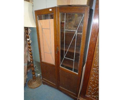 A 1920's oak glazed leaded Bookcase; six pane leaded doors with single oak lower panels revealing four fixed shelves on brack