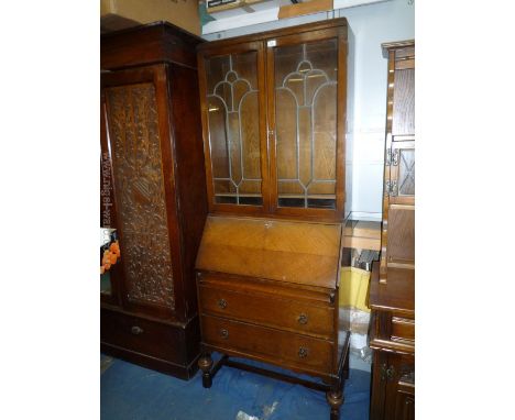 A 1940's Oak Bureau Bookcase having leaded glazed doors to the two shelf top, over fall with automatic lopers, over two drawe