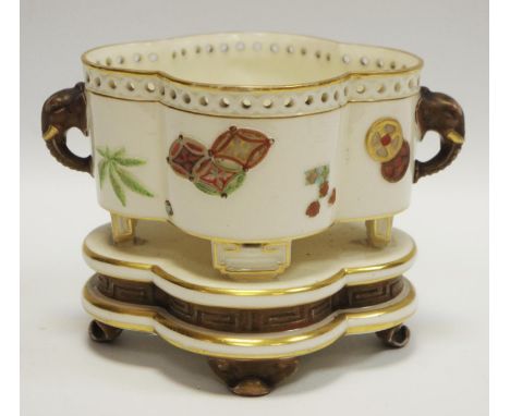 A Royal Worcester Aesthetic Movement quatrefoil shaped raised bowl with elephant mask handles decorated with oriental objects