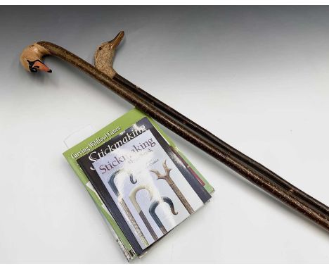 A carved and painted walking stick, the handle in the form of a swan's head, height 142cm, together with another similar, car