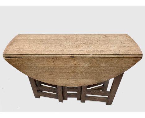 A light oak Cotswolds style gateleg supper table, the oval twin flap top raised on narrow supports, height 72cm, width 92cm, 