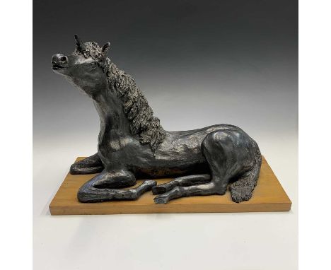 A ceramic sculpture of a unicorn, modelled in a recumbent pose with black finish, indistinctly signed Bolt? on pine base, ove