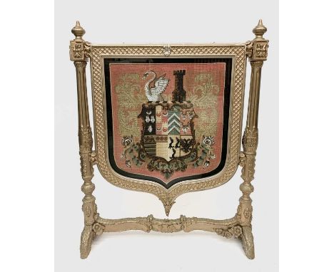 A Victorian gilt painted shield shape firescreen, the wool and beadwork panel featuring an armorial panel inscribed 'Mature' 