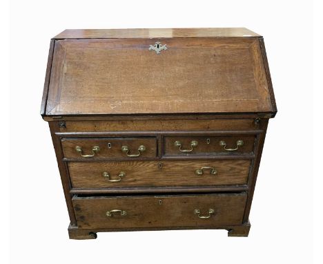 A George III oak bureau, the fall front enclosing a fitted interior, above two short and three long drawers, on bracket feet,