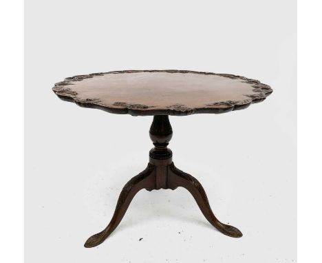 A George III mahogany tripod table, the snap top with foliate carved rim on an acanthus leaf carved baluster stem and downswe