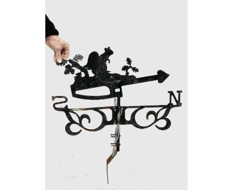 A mid 20th century black-painted steel wall mounted weather vane, surmounted by a squirrel. Height 71cm.