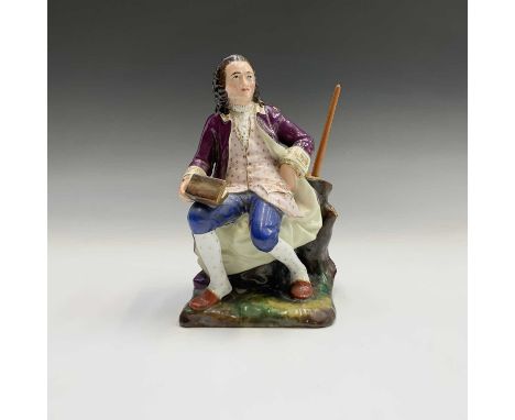 A 19th century French porcelain figural pen holder, modelled as a seated bewigged man holding a book (possibly a depiction of
