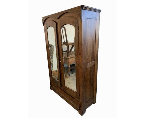 A German stained beech wardrobe, late 19th century, with a pair of mirrored doors above a single drawer on bracket feet, heig