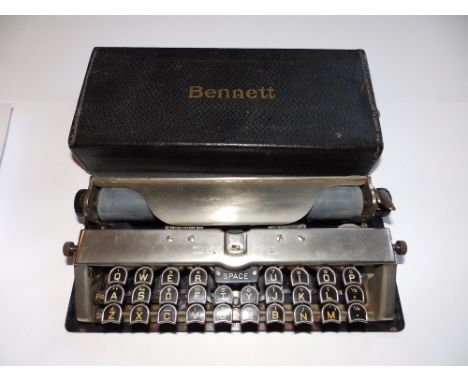 A Bennett portable typewriter in rectangular metal case.