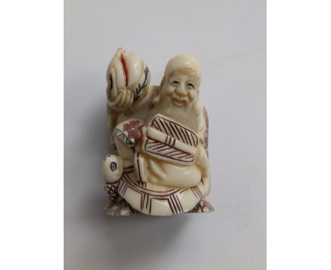 A Japanese ivory netsuke depicting sennin Tobosaku holding a peach and a fan, 2”.