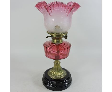 A Victorian cranberry glass oil lamp, with an etched glass shade, 46cm high