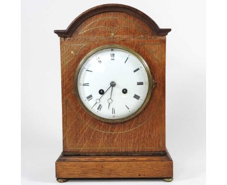 An early 20th century oak and brass strung cased mantel clock, with a white enamel dial, 33cm high