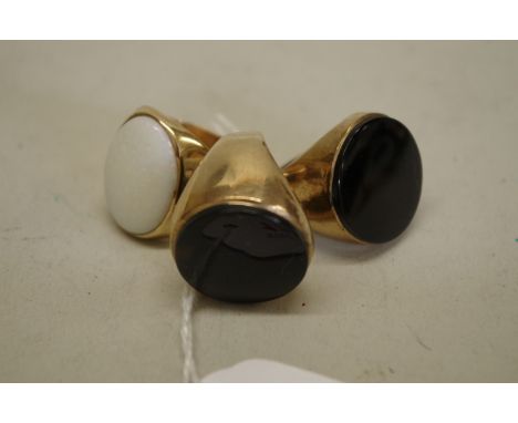 Two large onyx set gold signet rings, stamped 9ct; together with a similar oval opal unmarked example, 27.5g total weight. 